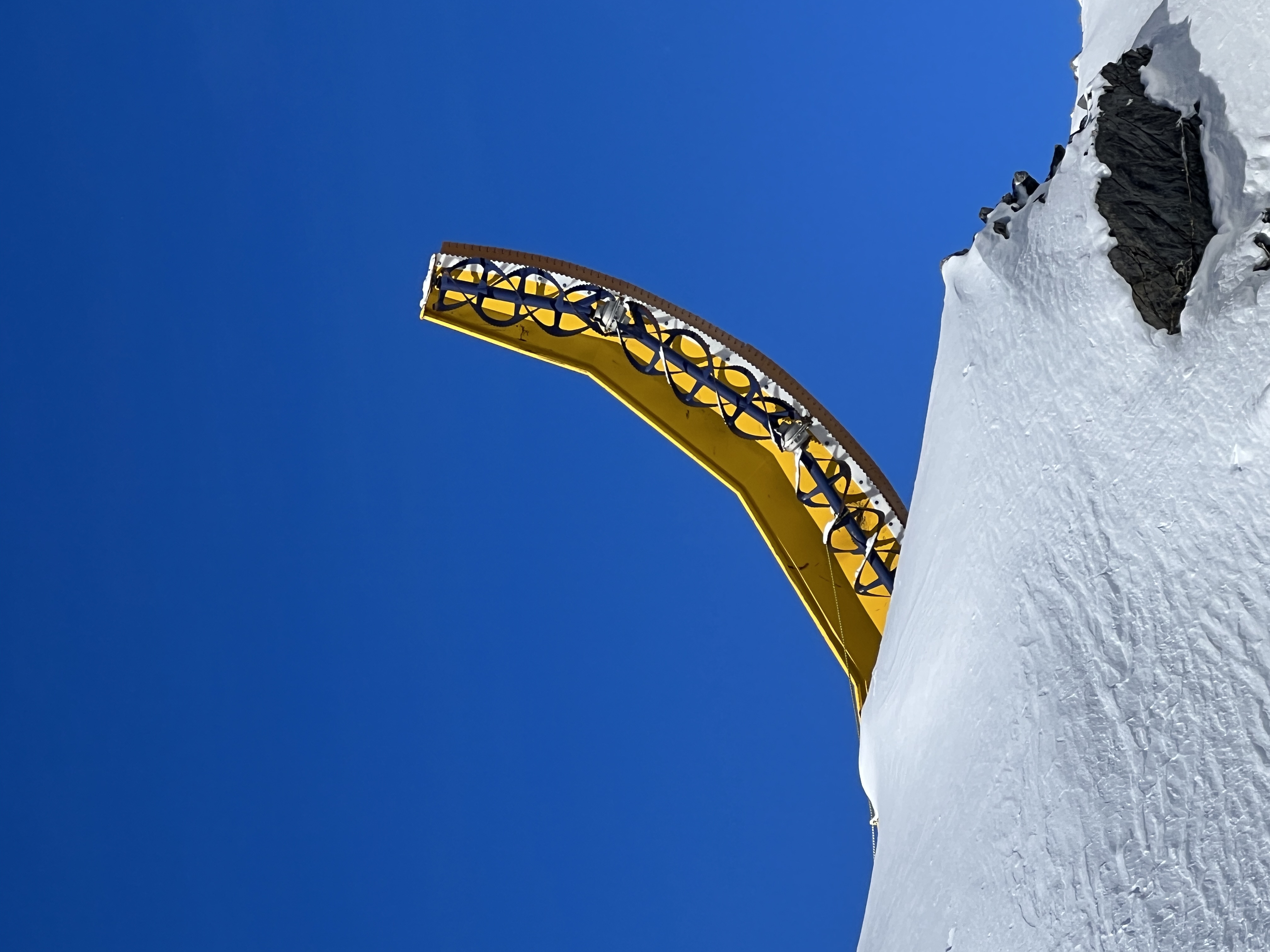 yellow crane surrounded by a blue sky and white snow